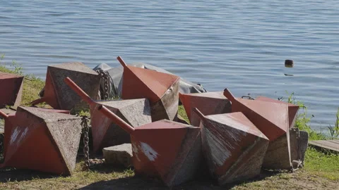 Group of old, weathered red navigation buoys with concrete bases and chains 스톡 동영상 347295195