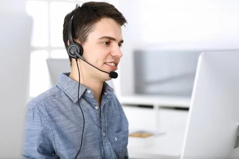 Group of operators at work. Call center. Focus on young man receptionist in Stock Photos