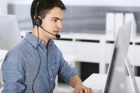 Group of operators at work. Call center. Focus on young man receptionist in Stock Photos