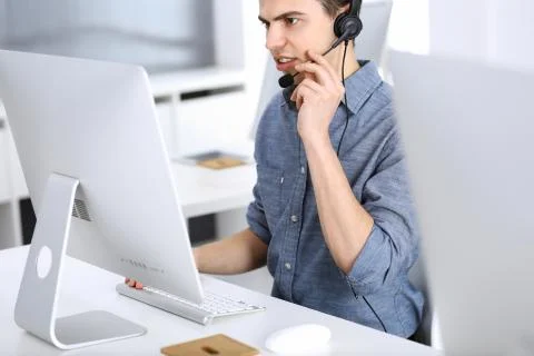 Group of operators at work. Call center. Focus on young man receptionist in Stock Photos