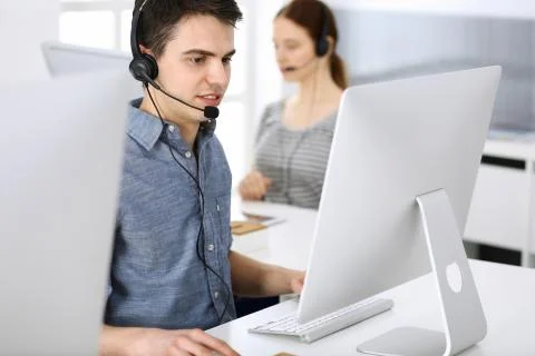 Group of operators at work. Call center. Focus on young man receptionist in Stock Photos