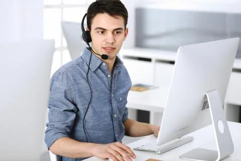 Group of operators at work. Call center. Focus on young man receptionist in Stock Photos