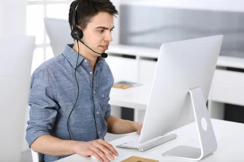 Group of operators at work. Call center. Focus on young man receptionist in Stock Photos