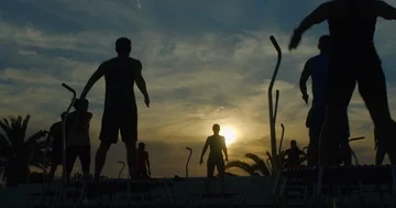 A group opf people doing a trampoline fitness class outdorrs at sunset. Vídeo Stock 85574131