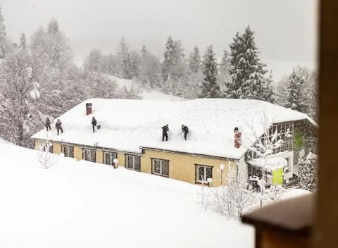 Group or team of workers cleaning or removes snow winter on the roof of a hou Stock Photos