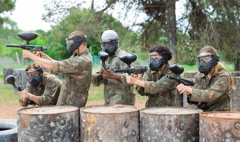 Group of paintball players aiming and shooting with guns Фото