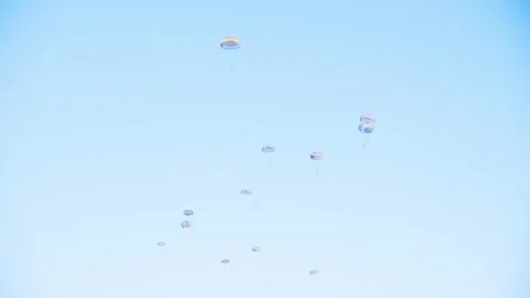 Group of parachutists in mid-descent form a coordinated pattern against a Video stock 286412964