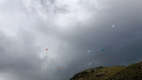 Group of paragliders gliding down mountain on a very cloudy day. Stock Footage 104489616