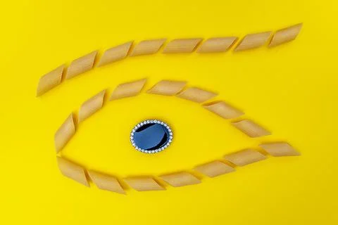 Group of pasta lined up in the shape of an eye with a jewel in the center Stock Photos