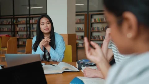 Group of pensive multicultural students studying and talking in library Stock Footage 250339525
