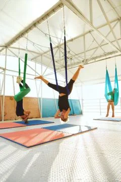 Group of people are practicing fly yoga with a hammock in outdoor studio Stock Photos