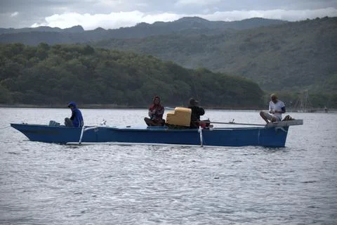 A group of people are sitting on a boat fishing in the sea Stock Photos