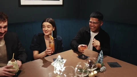 A group of people are sitting at a table in a bar, laughing Stock Footage 295996790