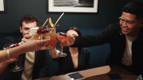 A group of people are sitting at a table, smiling and holding glasses of drinks Stock Footage 295996808