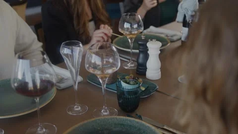 A group of people are sitting at a table with wine glasses and plates of food Stock Footage 306576712