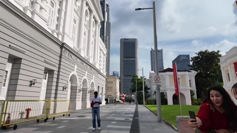 A group of people are walking down a sidewalk in front of a building Vidéo 318104470