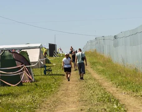 A group of people are walking down a dirt road Stock Photos