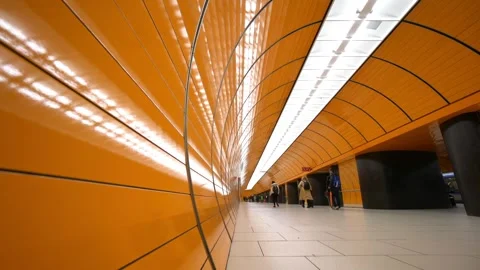 A group of people are walking through a tunnel with orange walls Stock Footage 314665342