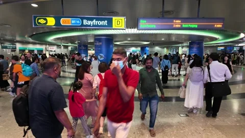 A group of people are walking through a MRT Bayfront train station Видео 315547852