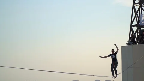 A group of people like balancing on a tightrope on top of a skyscraper, slow Stock Footage 90282473