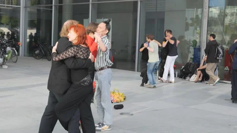 A group of people dancing closely outside a modern building. Stock Footage 311957217