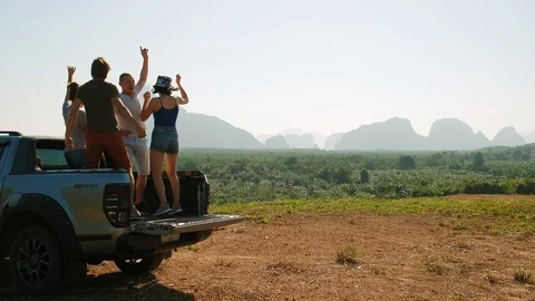A group of people dancing with hands up in the back of a pickup truck Stock Footage 128486084