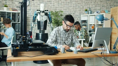 Group of people designing robot in office using 3d printer and computer Stock Footage 119565653