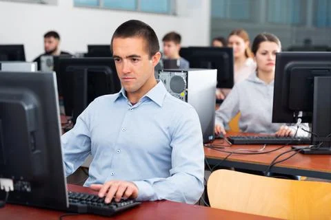 Group of people of different ages learning to use computers in classroom Stock Photos