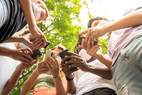 Group of people of different ethnicities using mobile phones and wearing prot Stock Photos