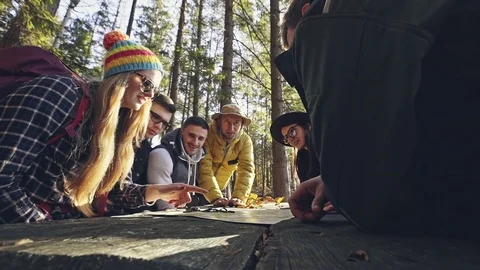 Group of people discussing over map in forest Stockbeeldmateriaal 83314414