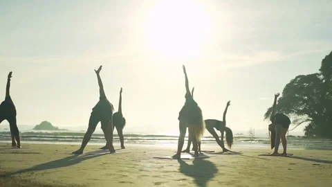 Group of people do yoga revolved triangle pose beach sunset rapid slow motion Stock Footage 84923337