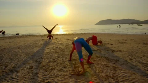 Group of people doing different yoga poses on the beach at sunset Stock Footage 75290235