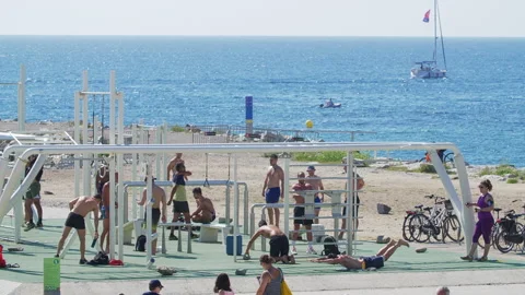 Group of People doing Physical Exercises at the Beach in Barcelona. A Boat at Stock Footage 135780545