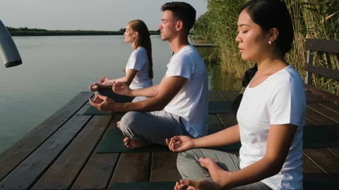 Group of people doing yoga exercises by the lake at sunset. Stock Footage 161016866