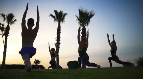 Group of people doing yoga on grass by the sea at dawn slow motion Stock Footage 63050936