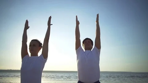 Group of people doing yoga pose namaste seaside sunrise rapid slow motion Stock Footage 78752036