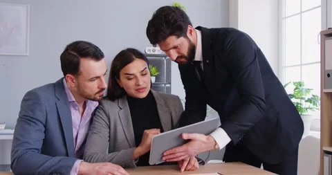 Group of people gathered around table, engaged in business discussion, pointing Stock Footage 334658977