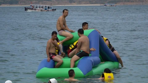 A group of people having fun playing in the inflatable aqua park. Entertainme Stock Footage 114806098