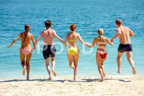 Group of people holding by hands each other and running in the sea Stock Photos