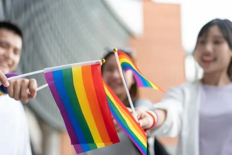 Group of people holding rainbow flags at an outdoor pride event. Promotes L.. Stock Photos