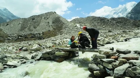 Group of people inserting the pole into the gushing river Stock Footage 77450738