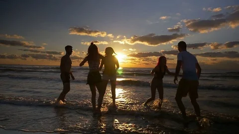 Group of people jumping dancing and having fun in the water on beach at sun.. Stock Footage 70611134