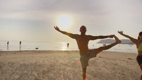 Group of people lord of the dance pose on beach at sunset Stock Footage 75289636