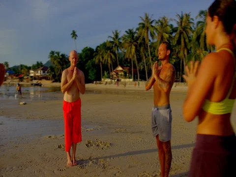 Group of people meditating on beach during sunset Stock Footage 75290837