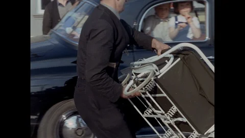 Group of people packing stuff on top of car roof, United Kingdom, 1967 Stock Footage 139242858