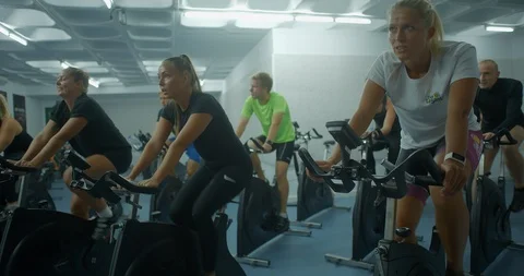 A group of people peddling exercise bikes in a gym Vídeo Stock 85535427