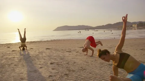Group of people performing different yoga poses on the beach during sunset Stock Footage 75291241