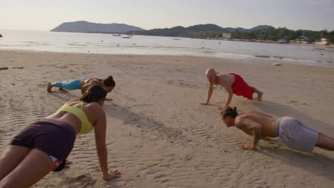Group of people performing surya namaskar on the beach Stock Footage 74779122