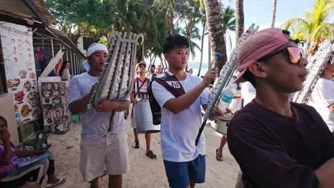 Group Of People Playing Bamboo Instruments During HIV Awareness March On Beach Stock Footage 334620585