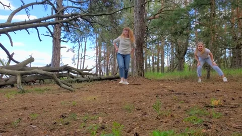 Group of people playing flying disc in a pine forest. Two young women Stock-Footage 134538795